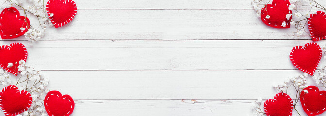 Valentines Day double border of cloth hearts and white flowers. Top view on a white wood banner background. Copy space.