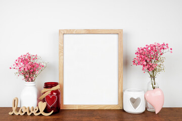 Mock up wood frame with Valentines Day decor and flowers. Wood shelf against a white wall. Copy space.