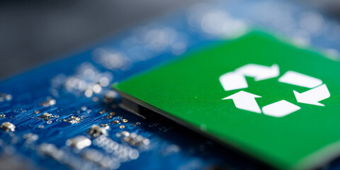 A green recycling symbol on a blue circuit board with blurry background of bokeh lights