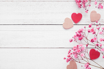 Valentines Day side border of wood hearts and pink flowers. Overhead view on a white wood background. Copy space.
