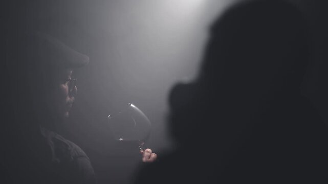 Photographer take photos of sommelier describing taste of red wine backlit by cinematic light scene. Degustation of alcoholic beverages, slow motion