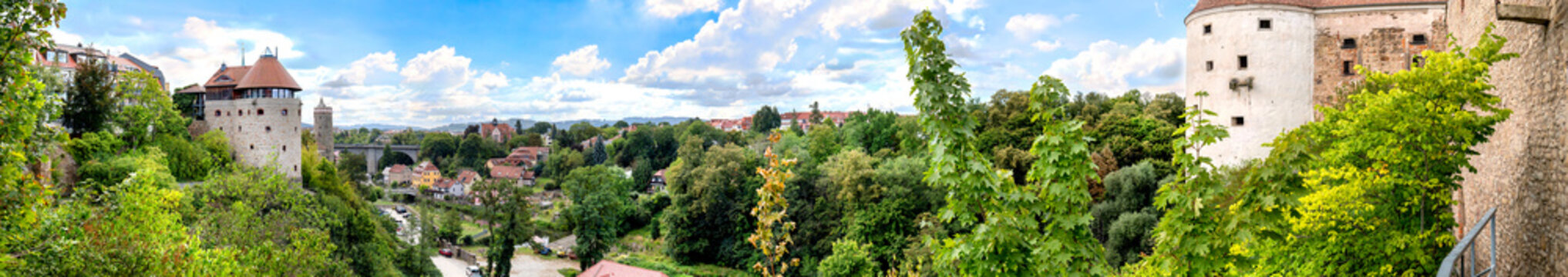 Bautzen, Germany - panoramic view of the old town and castle, wide view over river bank, towers, walls and wooded slopes under bright sky