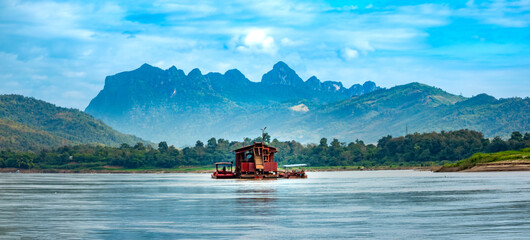 Dredging boat used for alluvial gold mining, vacuuming riverbeds to extract gold-bearing gravel, Mekong river, Luang Prabang, Laos.