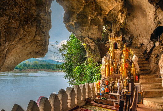 Scenic view from the lTham Tring (lower) cave of the Pak Ou Caves, confluence of the Ou and Mekong rivers, Luang Prabang, Laos, with historical golden buddha sculptures in the foreground