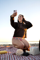 Young girl enjoying beach sunset taking selfie with phone