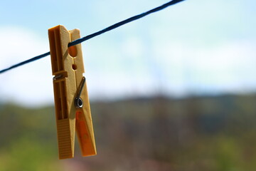 Close-up of a yellow plastic clothespin hanging from a blue string.