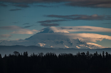 Dramatic clouds surround the magnificent volcanic mountain called Mt. Baker located in the Cascade range. The Cascade range a major mountain system in western North America, stretching over 700 miles.