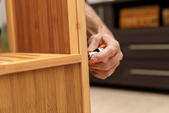 Close-up of male hands assembling wooden furniture using hand tools