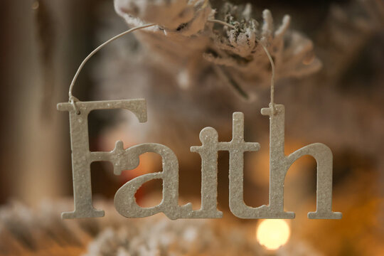 Christmas tree decoration for the winter holiday season. A tradition to hand ornaments on trees. The word Faith. 