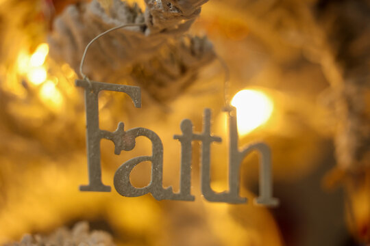 Christmas tree decoration featuring the word Faith for the winter holiday season. A tradition to hand ornaments on trees. 