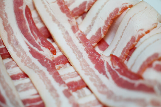 Raw bacon strips stacked across each other ready to be cooked for breakfast. 