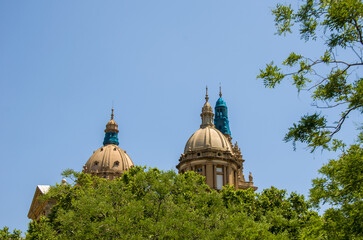 Historic domed building towers behind green trees on clear day © Kurulo