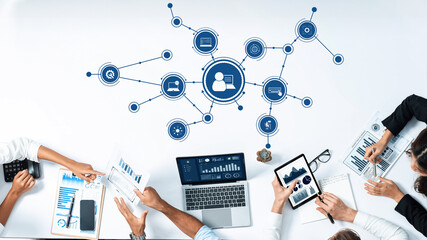 A diverse business team collaborates at a modern workspace, utilizing laptops and tablets to analyze data charts, enhance strategies, and improve digital communication. Amity