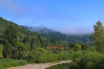 Serene landscape with misty morning fog over green meadow and mountains