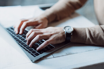 Close-up of a man's hands typing on a laptop keyboard 
