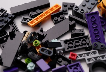 Naklejka premium Tambov, Russian Federation - January 01, 2026 A close-up shot of various colorful Lego plastic bricks and pieces scattered on a white surface.