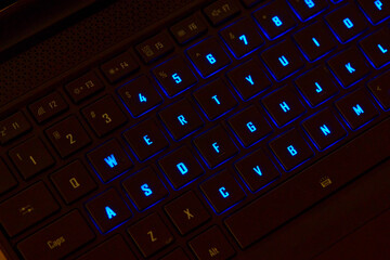 Close-up of a colorful RGB mechanical gaming keyboard illuminated in vibrant hues. Modern computer accessory designed for gaming setups, featuring customizable backlighting and sleek design. 