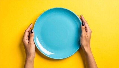 Hands holding a blue plate centered on a bright yellow background