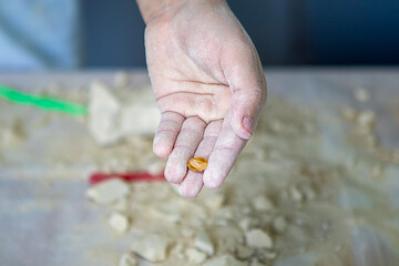 Close up of a flour-dusted hand holding a small almond during baking prep