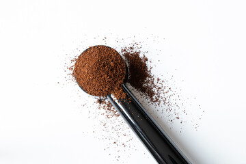 Ground coffee in a measuring spoon on a white background, coffee