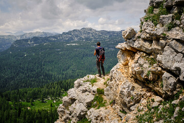 Mountain hiker standing at an edge of a cliff and looking at stunning Triglav mountain rocky peaks