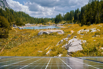 Scenic lake on Triglav mountain in Slovenia, autumn colored grass and foreground solar panels from...