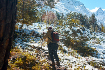 Girl with backpack ascends mountains during snowfall, showing determination in winter alpine challenge.