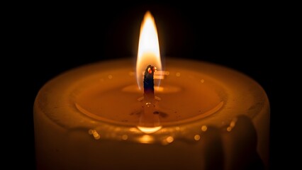 A close-up shot of a burning candle, radiating a warm, inviting glow. The flickering flame dances against a dark background, creating a sense of serenity and contemplation. 