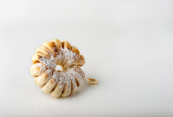 Puff pastry bun in powdered sugar on white glass, homemade baking, space for text.