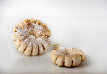 Two puff pastry buns dusted with powdered sugar on white glass, homemade baked goods, space for text.