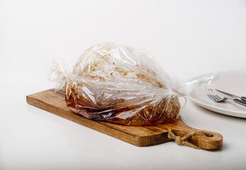 Meat in a baking bag on a wooden board, space for text.