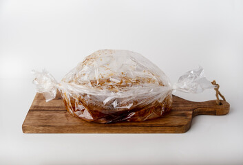 Meat in a baking bag on a wooden board, space for text.