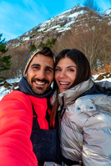 Happy couple enjoying winter mountain vacation taking selfie