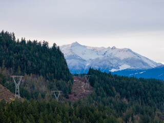 Snowy Mountain Range Over Dense Forest in BC Canada With Power Lines at Twilight