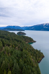 Naklejka premium Serene Mountain Lake Overlooking Dense Forests and Snowy Peaks in British Columbia, Canada