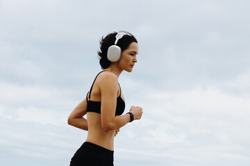 Caucasian young female jogging with headphones on a cloudy day