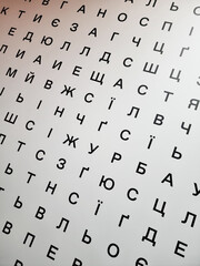 Optical Vision Chart Concept - Ukrainian Alphabet. Minimalist abstract typography background with cyrillic letters. Diagonal View of a white geometric letter wall with black letters.