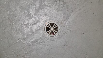 Drain hole in a concrete floor at an indoor location showing signs of wear and usage with surrounding grey cement area