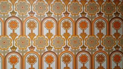 Colorful flower pattern in retro design displayed on a wall in a vintage setting during daylight hours