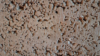 Surface of a textured wall showing many small holes and uneven spots