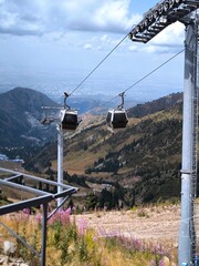 Cable car cabins over a mountain valley with a city in the background