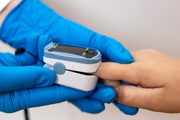 Medical worker in gloves measuring patient blood oxygen level using pulse oximeter