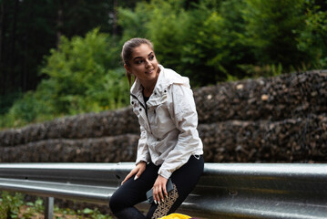 Young woman in sportswear resting by a guardrail in a forest setting