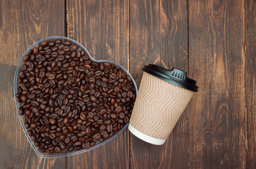 Aromatic roasted coffee beans with take-out mock-up paper cup. dark background, top view, copyspace.