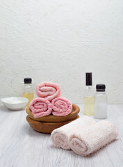 Clean pink towels, houseplant, shampoo, conditioner, and soap arranged on a white table with room for product text.