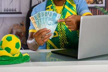 Brazilian fan shows off prize money won alongside laptop and soccer ball.