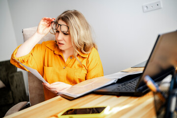 Business woman reviewing tax documents with laptop at home office. Financial compliance and accounting control process.