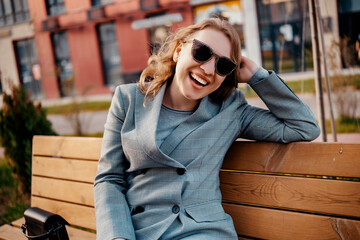 Business woman engineer laughing on bench, spring urban park, confident corporate leader, tech career happiness, modern lifestyle portrait.