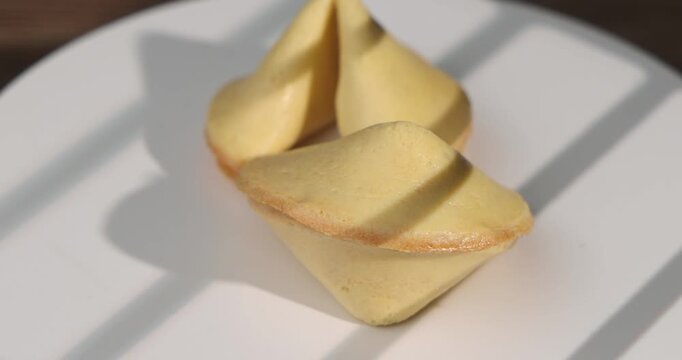 Top view of several fortune cookies rotating on a wooden table with black background for Chinese New Year and luck concept videos.