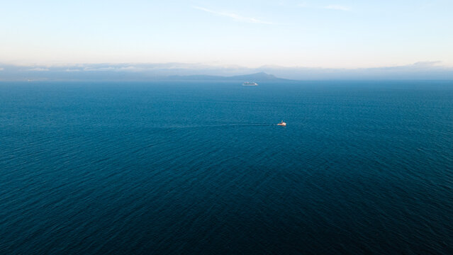 Minimal open ocean with small boat and distant horizon